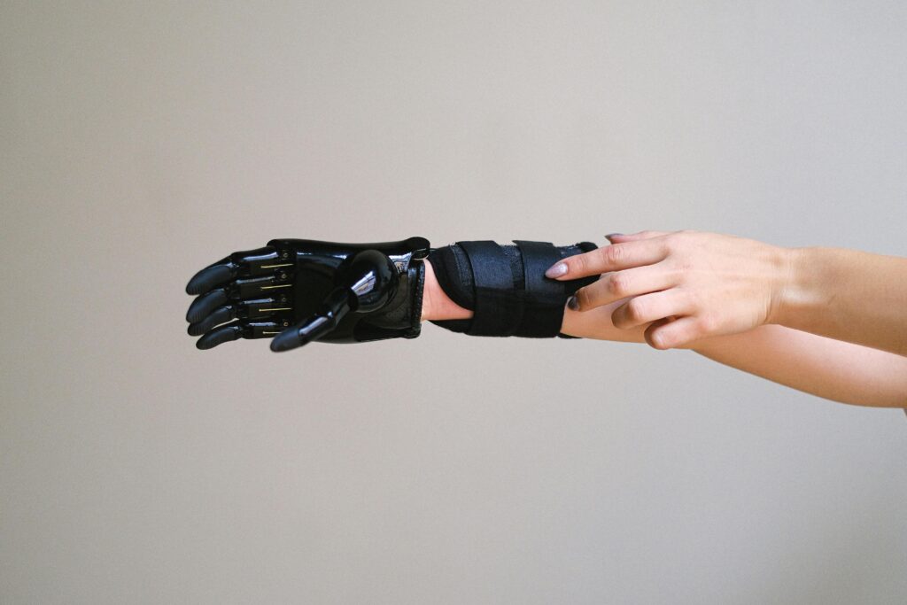 pexels-photo-5614225-5614225 Close-up of a person adjusting a high-tech prosthetic arm against a gray background.